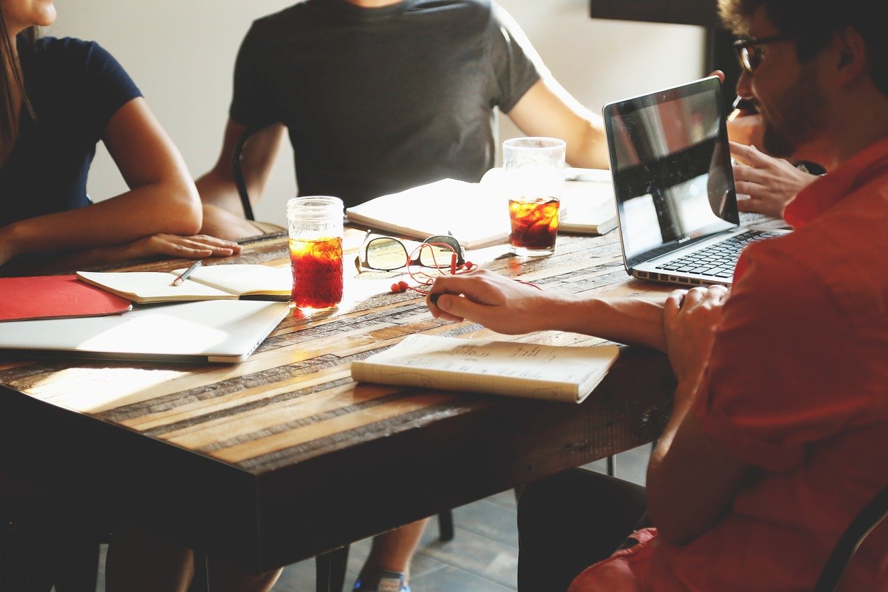 Four people meeting in person around a table. Image from Pixabay
